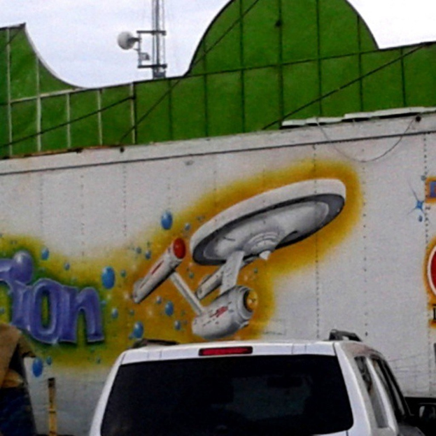 Ein Auto vor einer Wand mit einem Bild darauf geparkt.