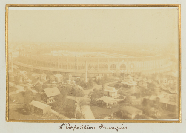Altes Schwarz-Weiß-Foto eines Stadions in städtischer Umgebung mit umliegenden Gebäuden, Bäumen und Strommasten, das unten einen Text zeigt.