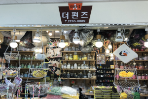 Ein unordentlicher Laden in Seoul zeigt verschiedene Gegenstände wie Körbe, Lampen, Flaschen und Spielzeuge auf Regalen, mit einem Schild oben, das anzeigt, dass es einer der besten koreanischen Läden ist.