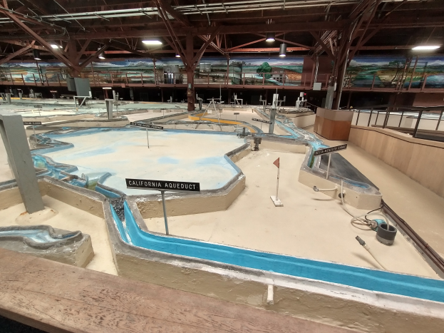 Indoor-Wasserpark mit mehreren Wasserrutschen, Deckenleuchten, Wandgemälde und einem Minigolfplatz.