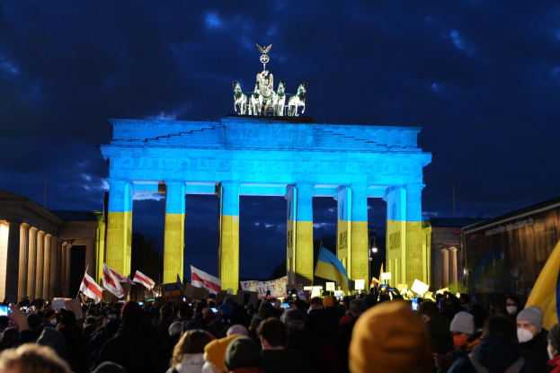 Eine Menschenmenge steht vor dem Brandenburger Tor in Berlin, Deutschland, mit Fahnen und Plakaten in den Händen, auf der rechten Seite des Bildes ein Banner.