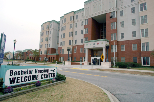 Außenansicht eines Bachelor Housing Welcome Center mit Gebäuden, Straßeninfrastruktur, Fahrzeugen, Grünflächen und einem klaren Himmel.