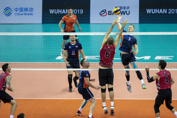 Männer spielen Volleyball auf einem Court mit Netz und Ball in der Luft während des BWU-Männer-Volleyball-Weltmeisterschafts 2019.