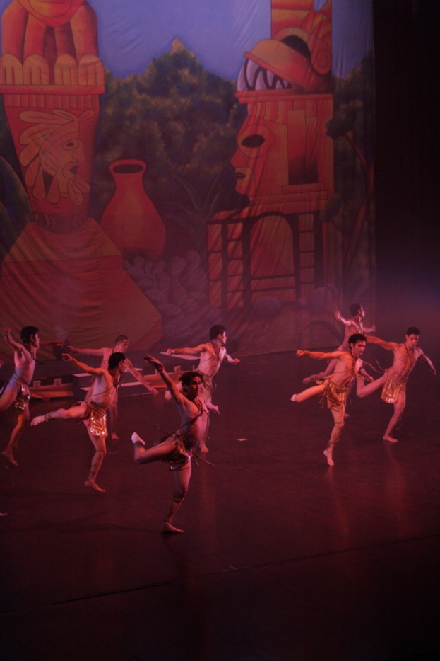 Menschen in Kostümen, die auf einer Bühne mit einem Vorhanghintergrund auftreten.