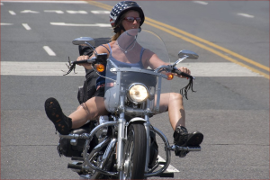 Eine Frau mit schwarzem Helm fährt auf der Straße Fahrrad.