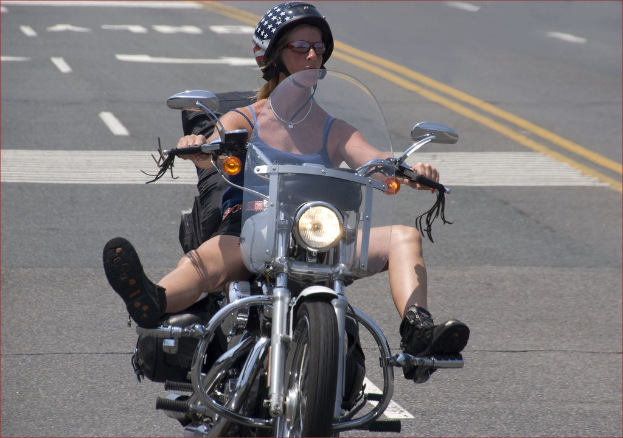Eine Frau mit schwarzem Helm fährt auf der Straße Fahrrad.