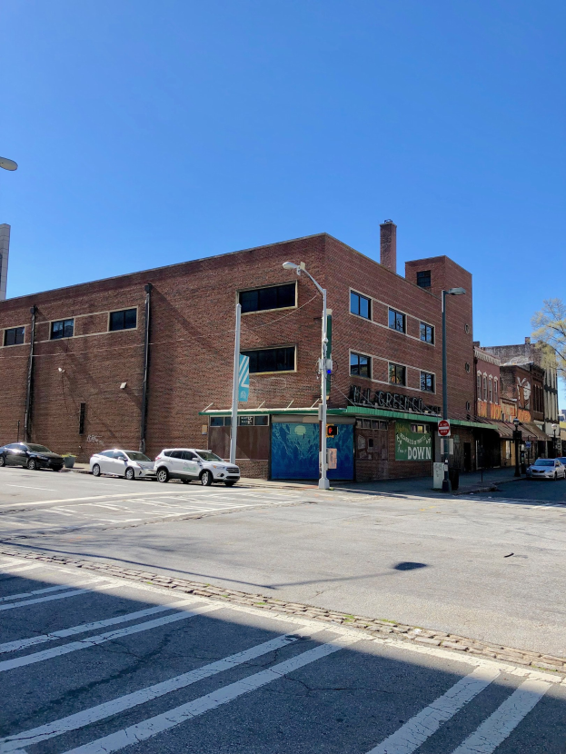 Leere Straße mit parkenden Autos, Laternen und Gebäuden, gesäumt von Bäumen unter einem klaren blauen Himmel, mit einem Wasserzeichen für ein kommerzielles Objekt zum Verkauf an 715 W Main St, Chicago, Illinois 60611, USA.