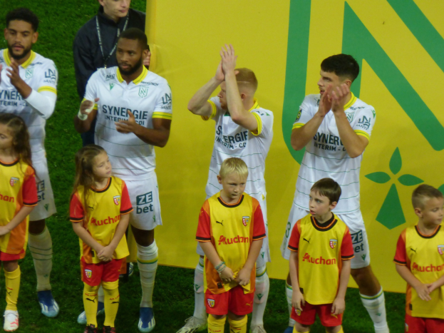 Eine Gruppe von Fußballspielern in Uniform klatscht auf einem Ligue-1-Feld nach einem Sieg.