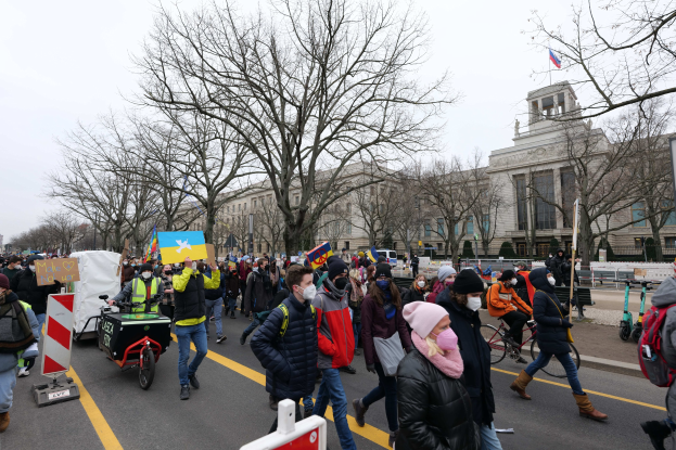 Eine große Gruppe von Menschen marschiert bei einer Protestaktion in Washington, D.C. am 21. Januar 2020, einige halten Schilder und andere fahren Fahrräder, mit Bäumen und einem klaren blauen Himmel im Hintergrund.