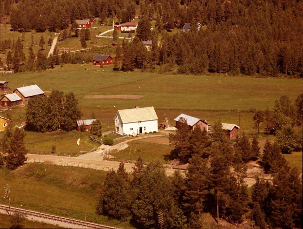 Luftaufnahme einer kleinen Stadt umgeben von grünen Feldern, Bäumen, Häusern, Straßen und Strommasten, identifiziert als Farm in Montana.