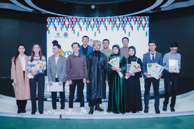 Gruppe von Menschen auf einer Bühne mit Blumensträußen und Urkunden, vor dem Hintergrund 'Jugend-Solar-Awards 2019'