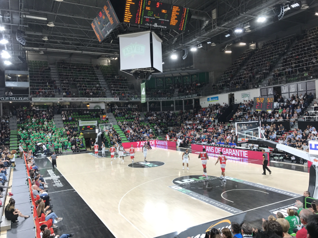 Basketballspiel in einer großen Arena mit Zuschauern, mit den Teams Asvel und Galatasaray, wie auf dem Scoreboard zu sehen ist.