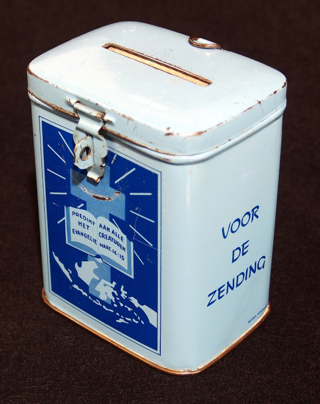 Eine weiße und blaue Blechspardose mit einer blauen und weißen Aufschrift "Voor de Zending" auf einer schwarzen Oberfläche.