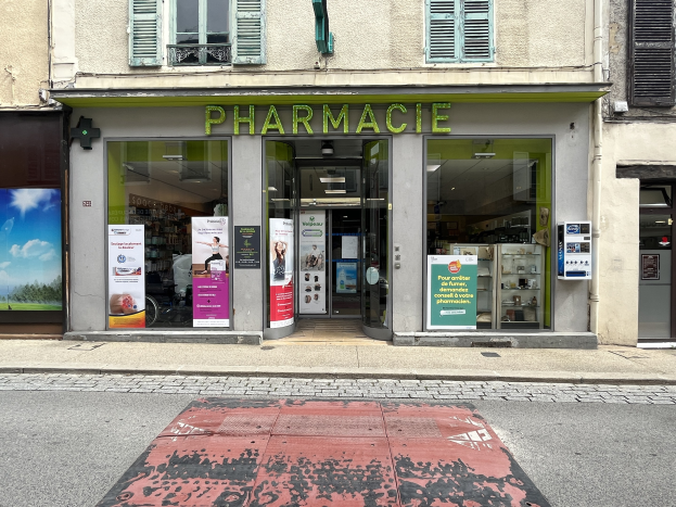 Apotheke mit Glaswänden und -türen, Plakate an den Wänden, an der Ecke einer Straße gelegen mit einer Straße unten.