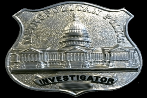 Ein silbernes Polizeibadgebnis mit der Aufschrift "Investigator" vor einem weißen Hintergrund.