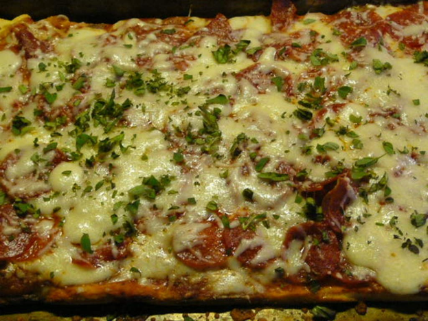 Ein Stück Nahrungsmittel mit geschmolzenem Käse auf einem Tablett.