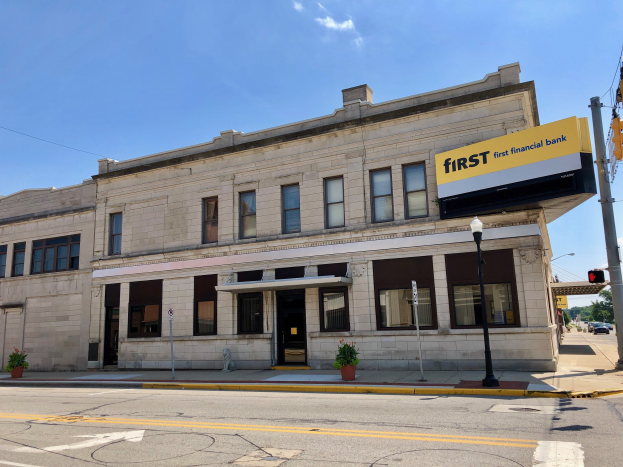 Großes Gebäude mit einem "First Financial Bank"-Schild, umgeben von Straßeninfrastruktur, Fahrzeugen, Grünflächen und einem bewölkten Himmel.